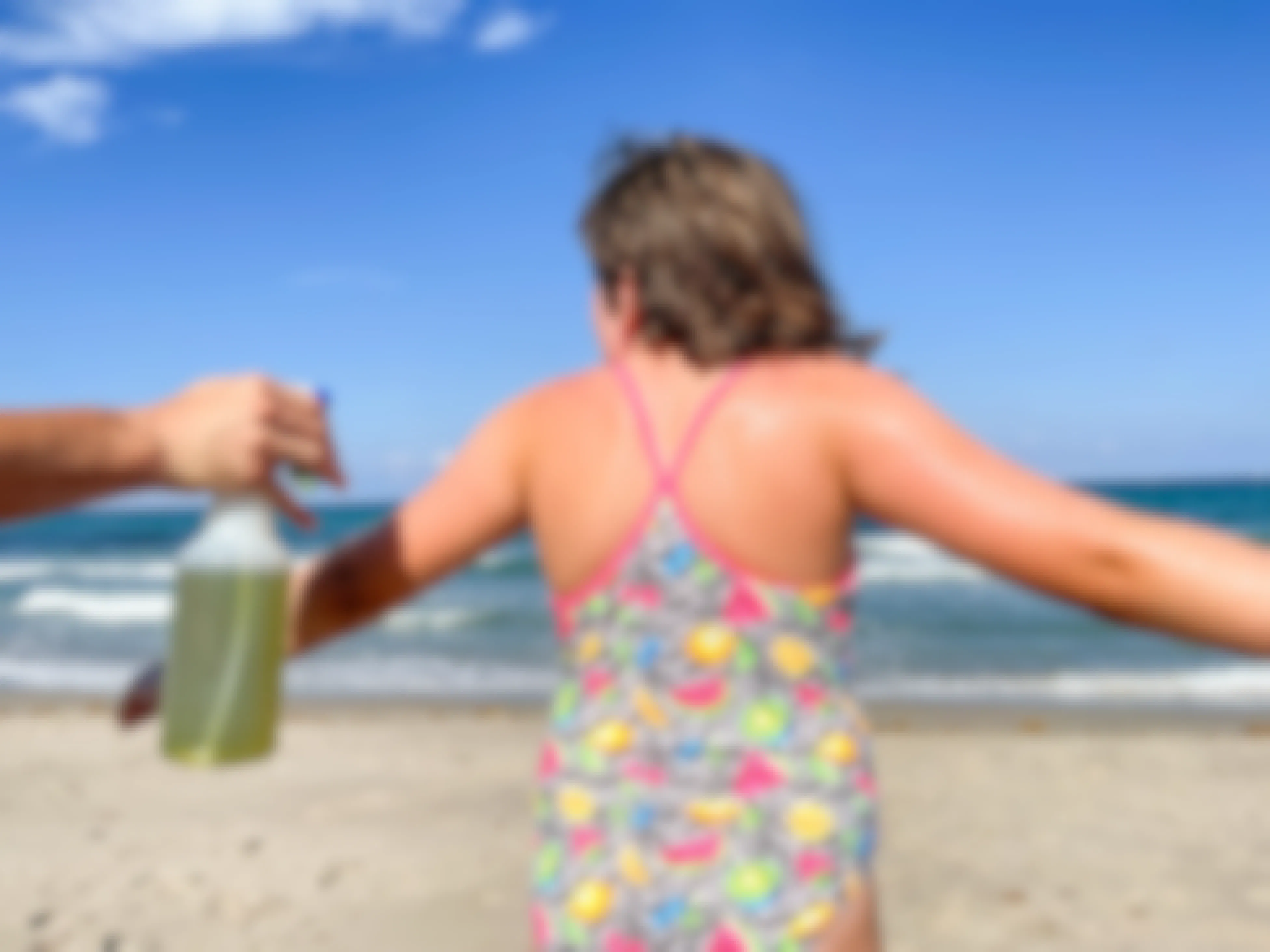 someone spraying green tea on a girl at the beach