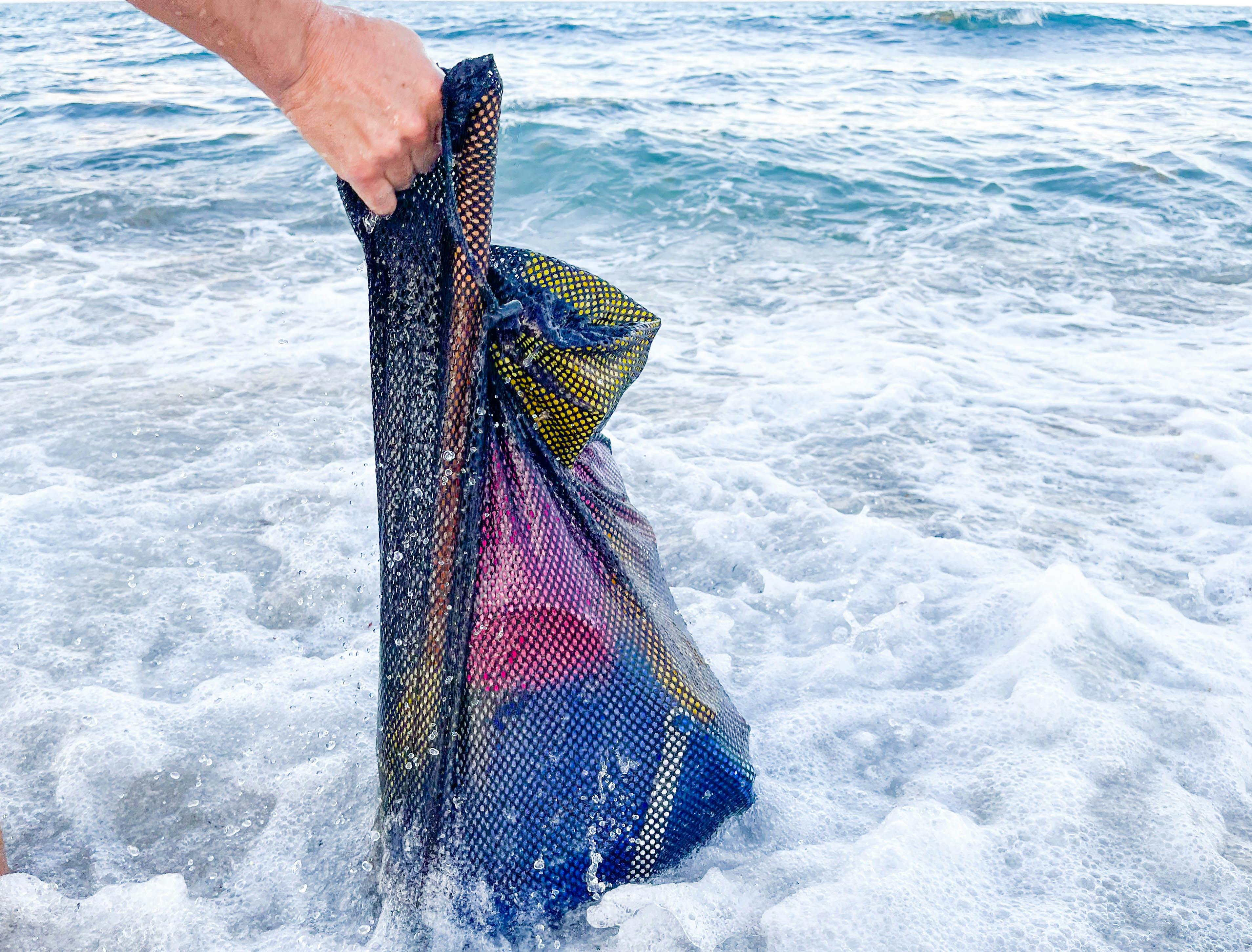 mesh bag with sand toys being washed in the ocean water