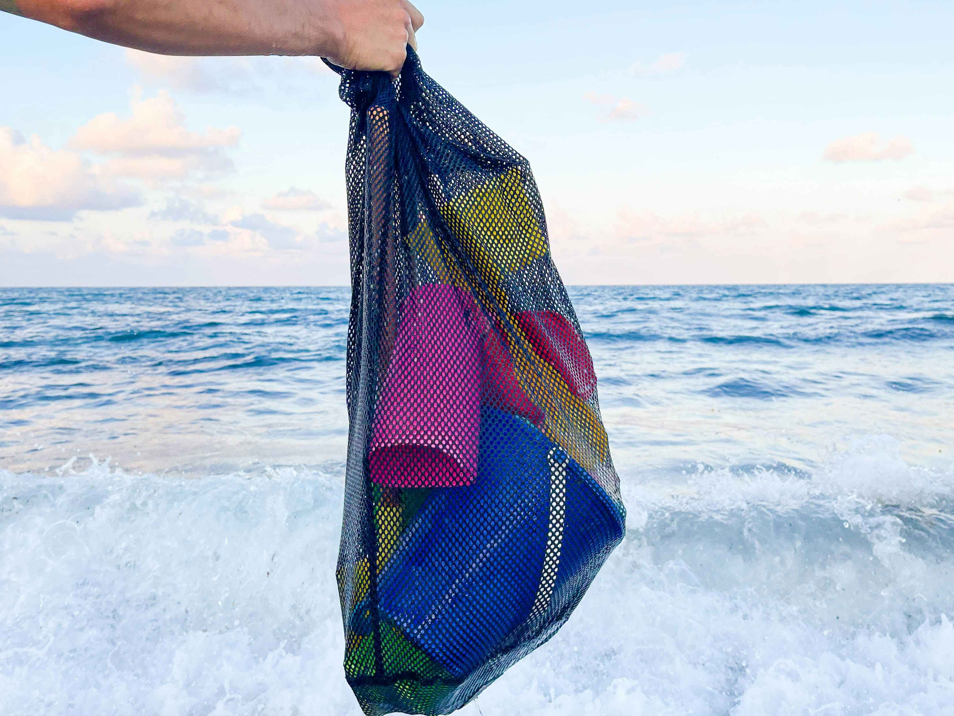 mesh bag full of toys held over ocean water