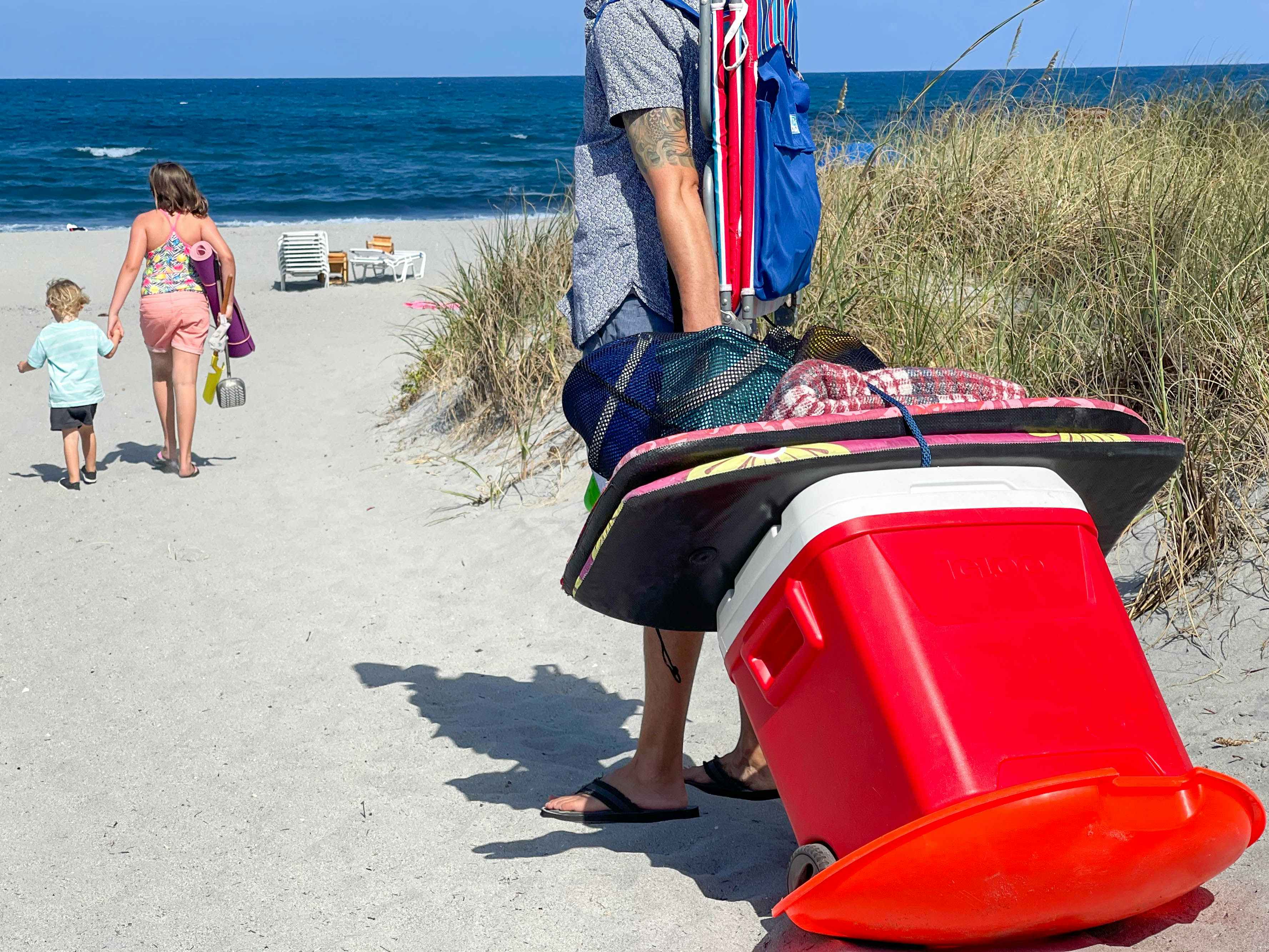 Man pulling a cooler and beach supplies with a sled.