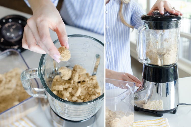 A person putting clumps of brown sugar into a blender.