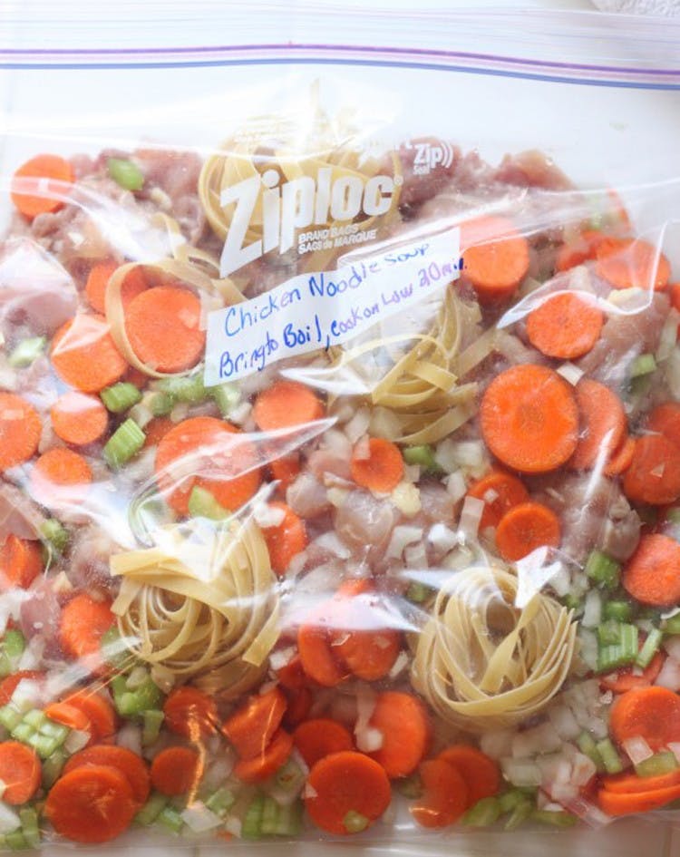 A Ziploc bag with noodles, carrots, celery, chicken and onions