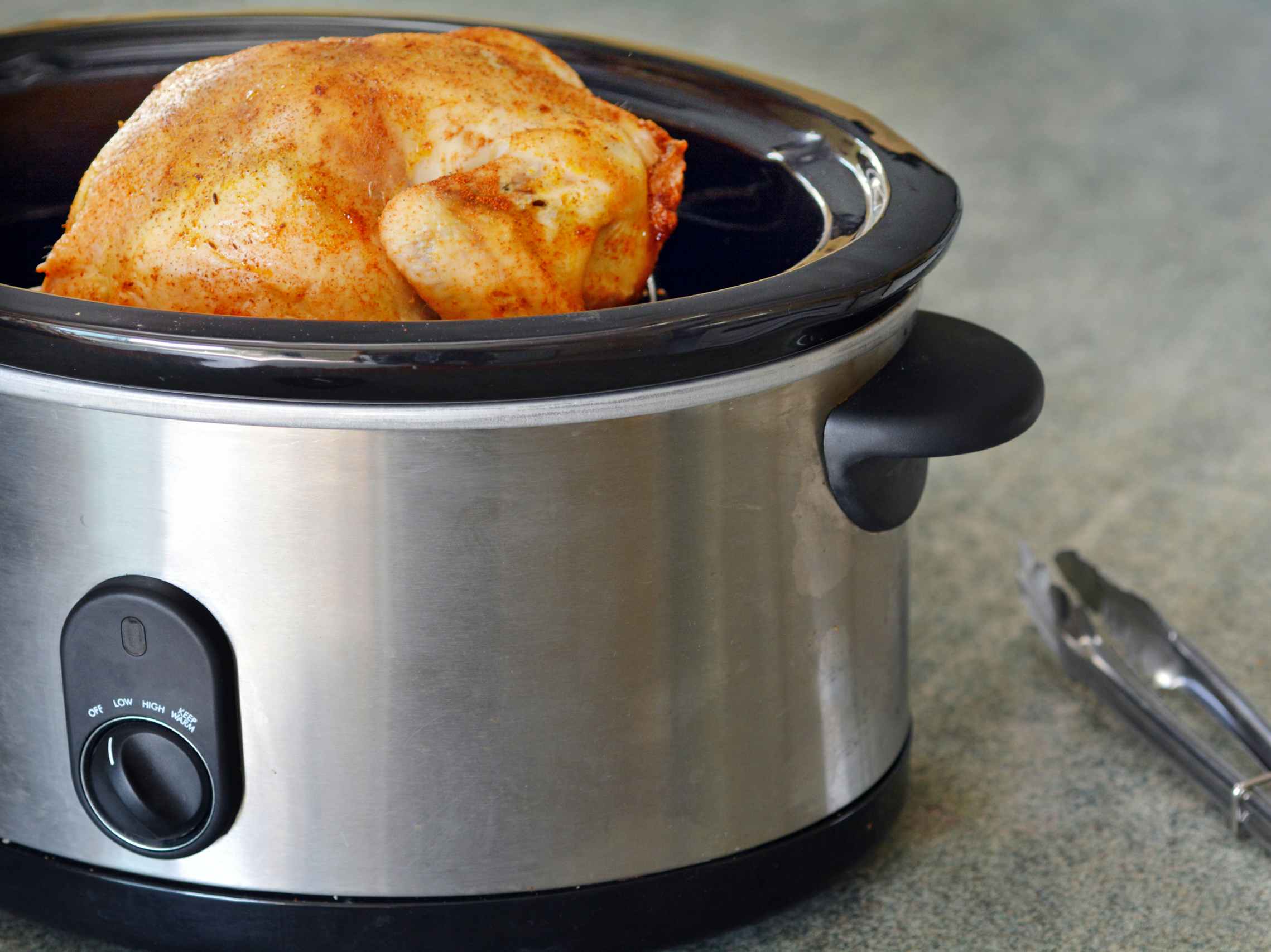 A whole chicken cooking in a slow cooker.