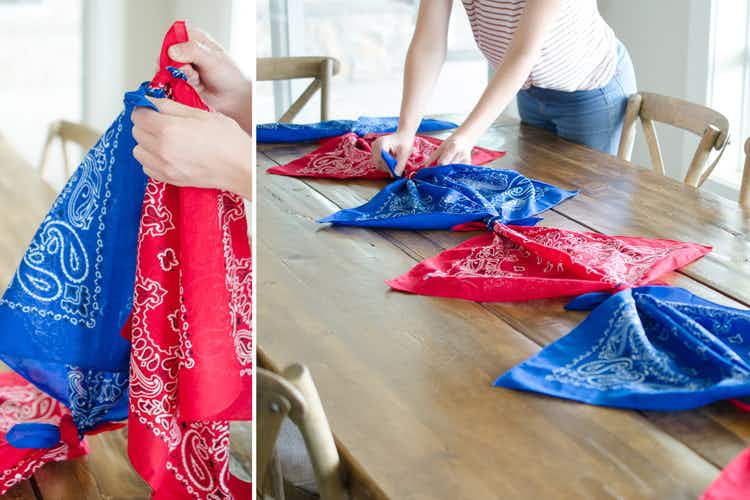 A person's hands tying red and blue bandanas together and placing them across a table like a runner.