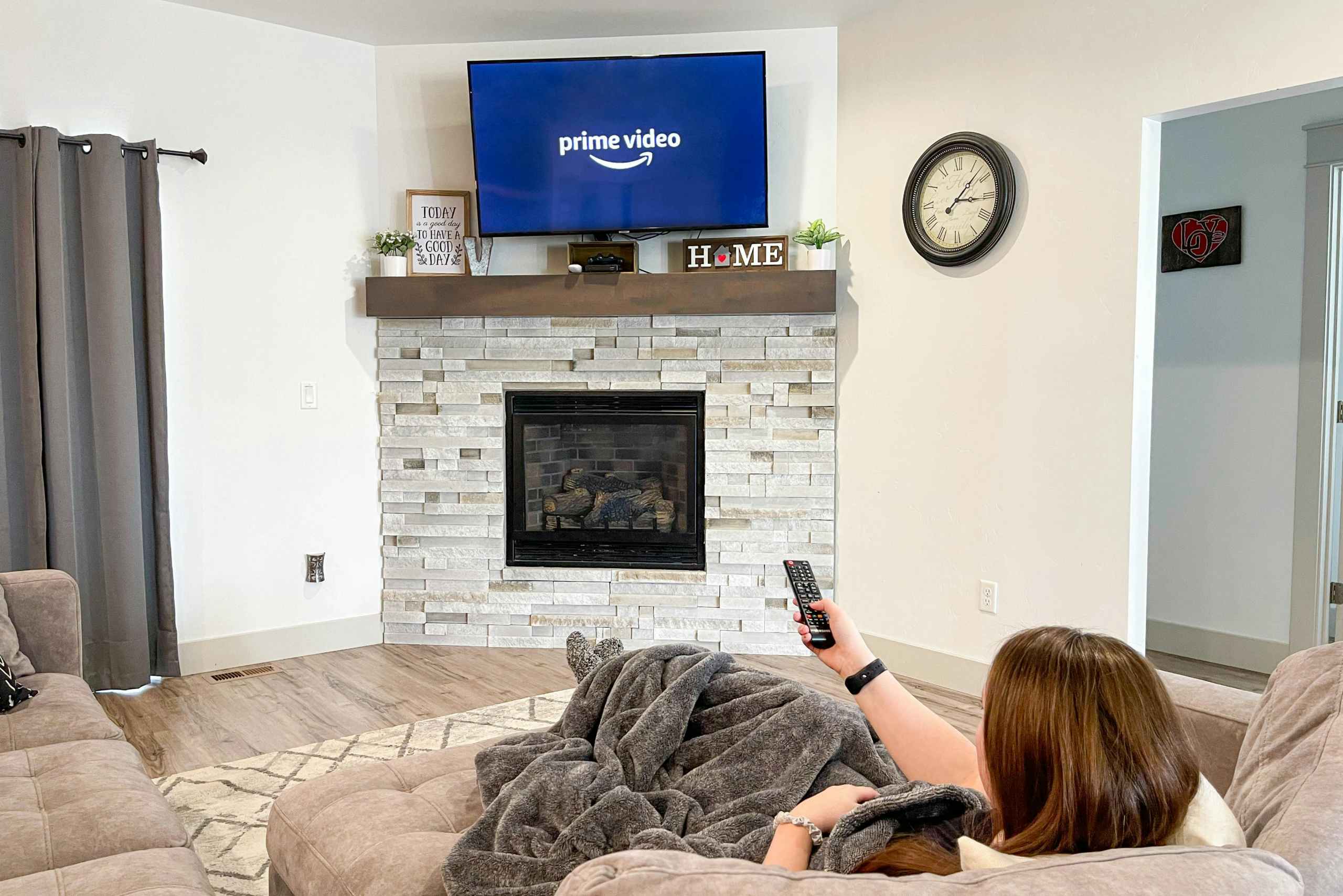 Someone sitting on a couch, pointing a remote at a TV with the Amazon prime video app opening