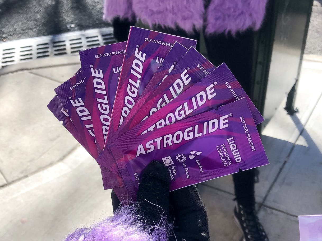 A person's hand holding a bunch of Astroglide free samples.