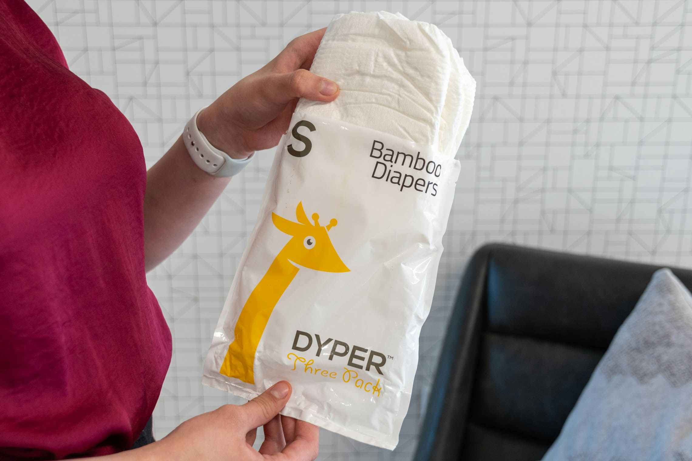 A woman holding up a Dyper bamboo diaper sample package.