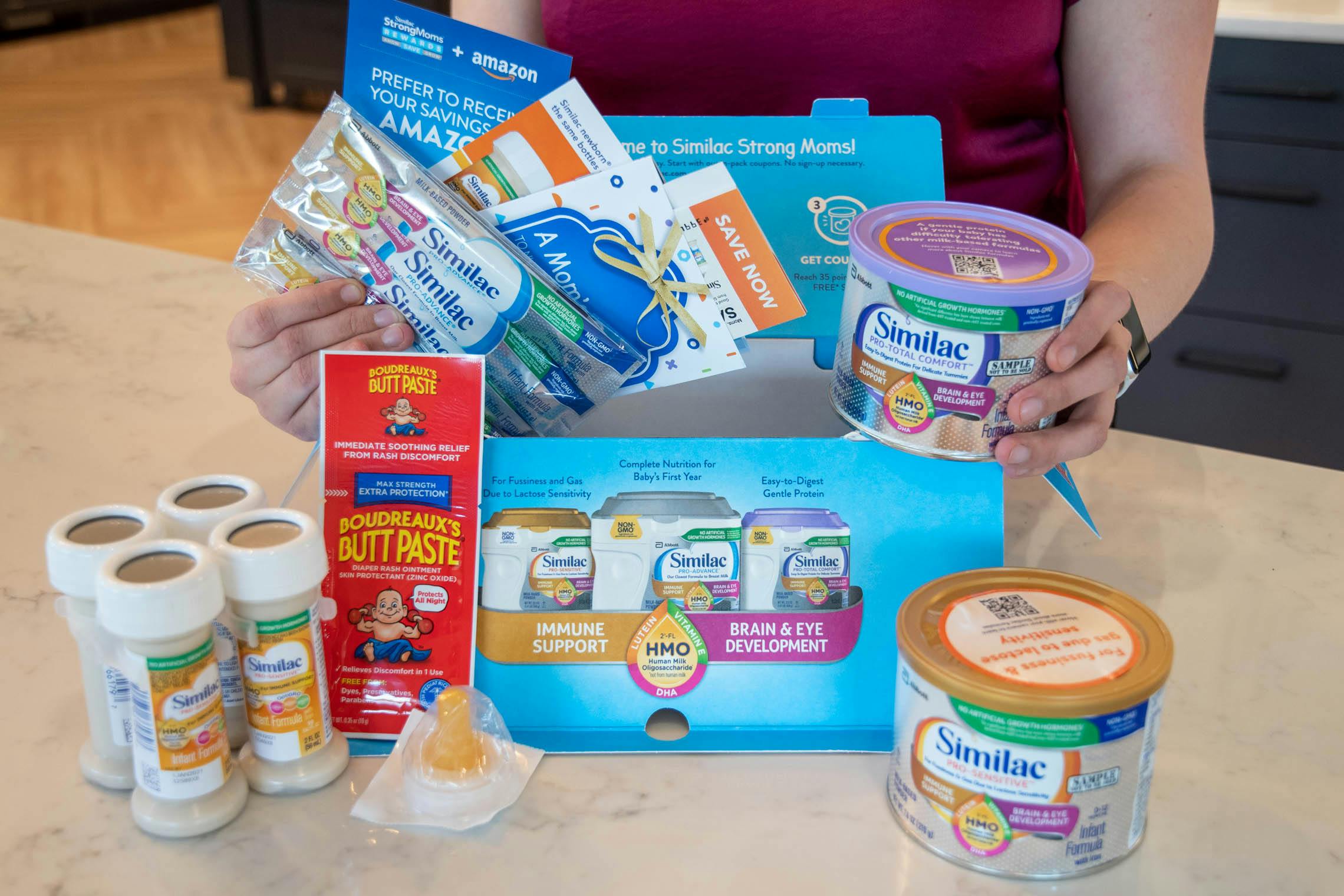 A person holding items from a little gift Similac formula box.