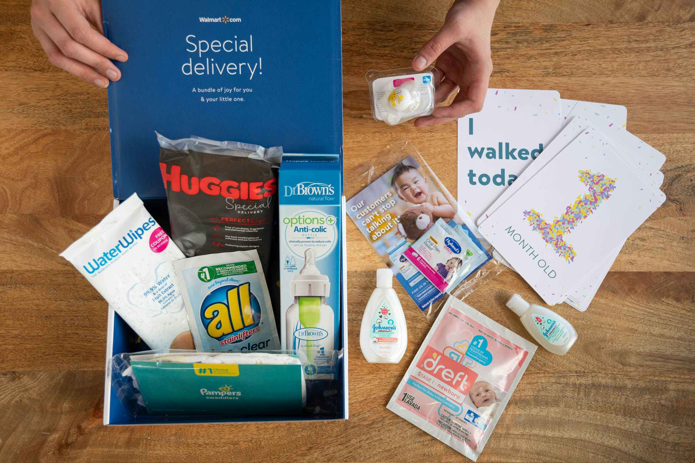 An open Walmart Registry baby welcome box with baby products inside and on the table next to it.