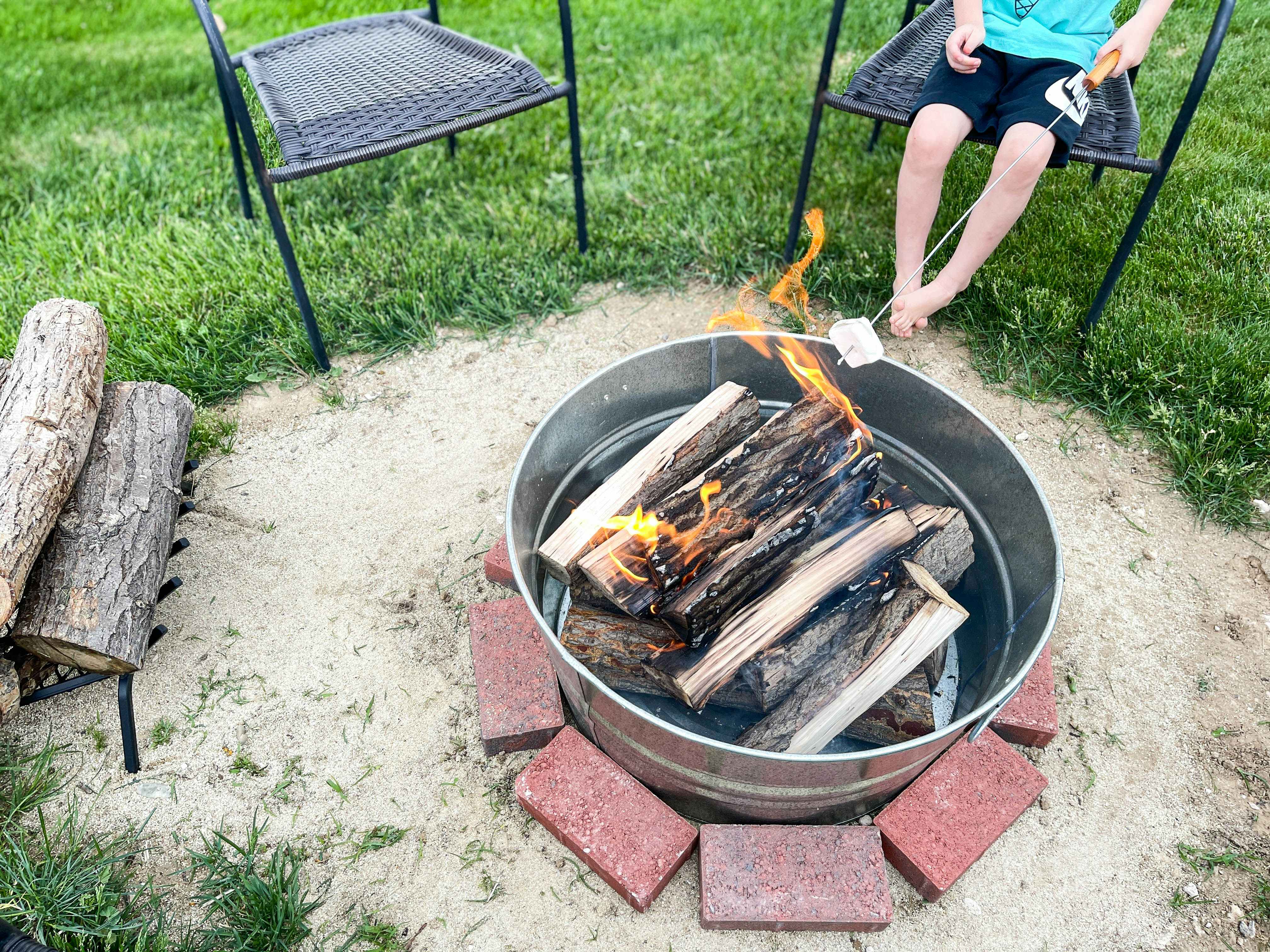 diy firepit in backyard from a galvanized pale with kids cooking marshmellows