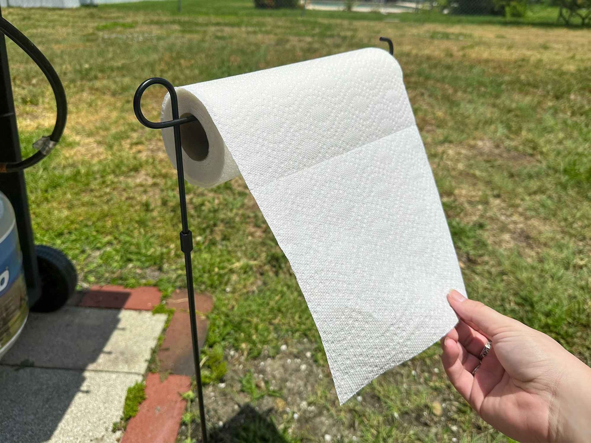 Someone taking a paper towel from a garden flag pole in the backyard