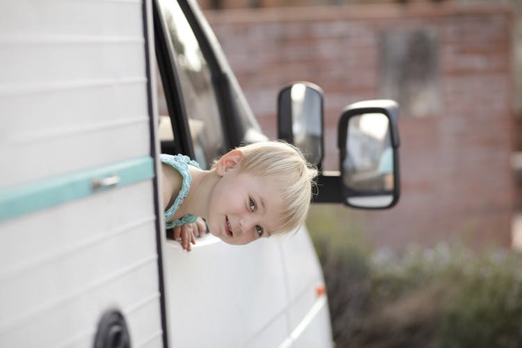 A child sticking their head out of the window on an RV.