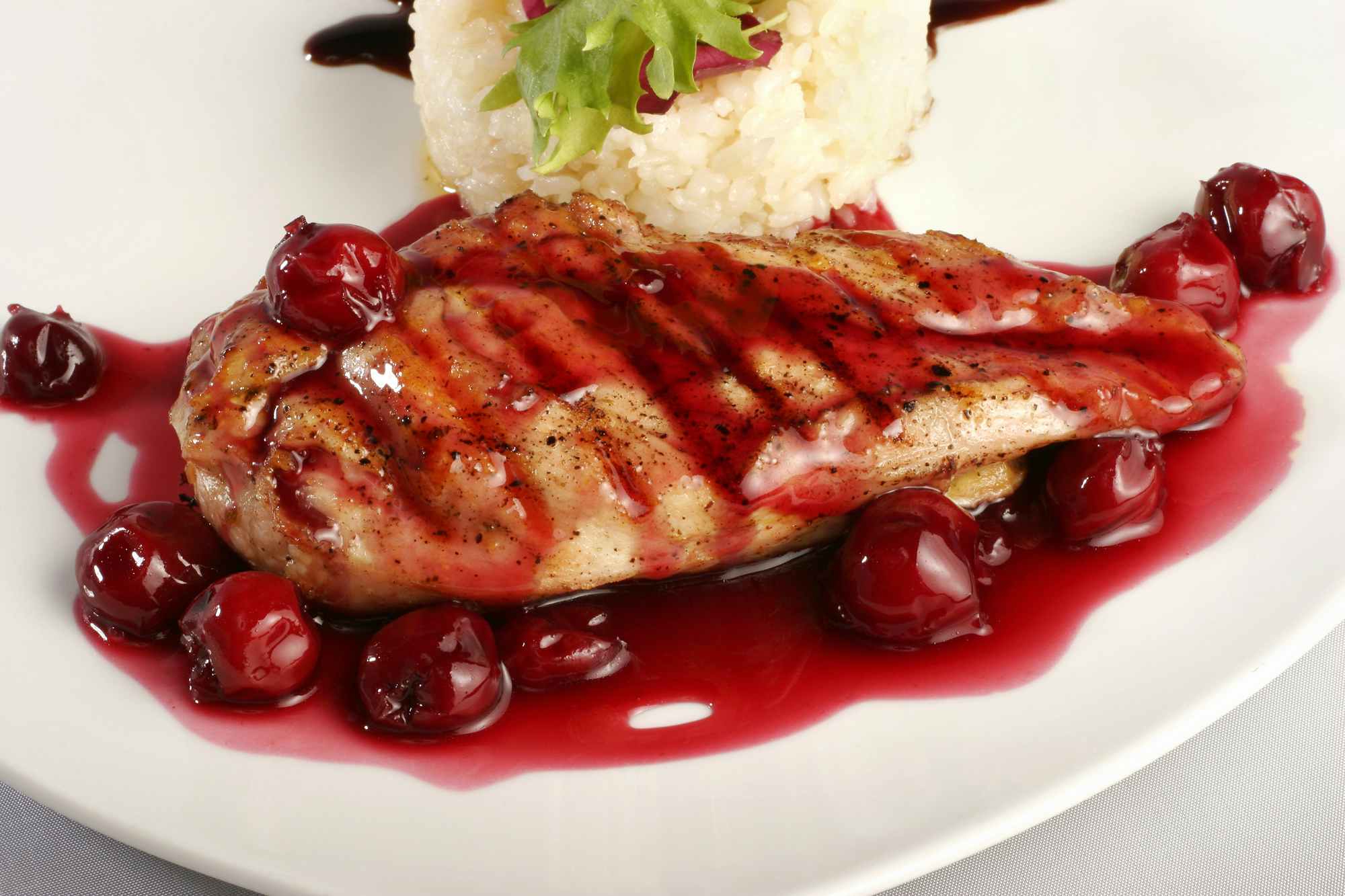 A plate of grilled chicken with cherry sauce