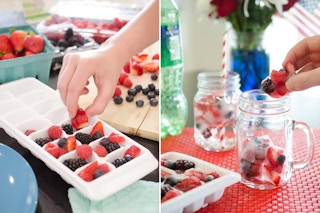 A person's hand taking frozen berries out of an ice tray and putting the berry ice cubes in drink glasses.
