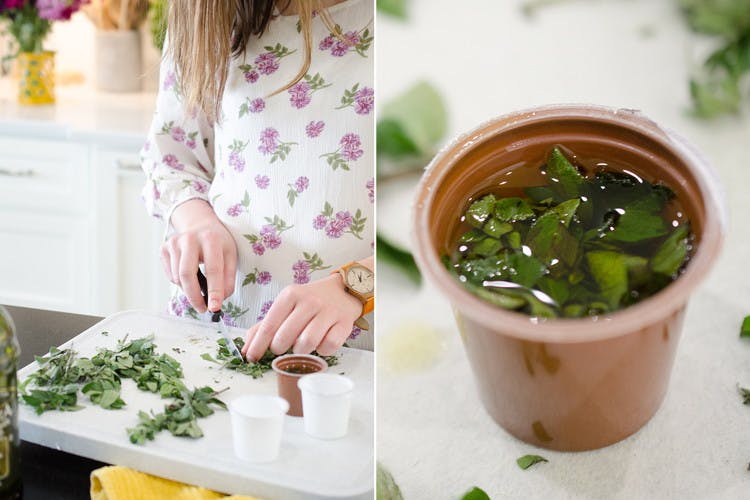 A person chopping herbs next to a K-cup with herbs and olive oil.