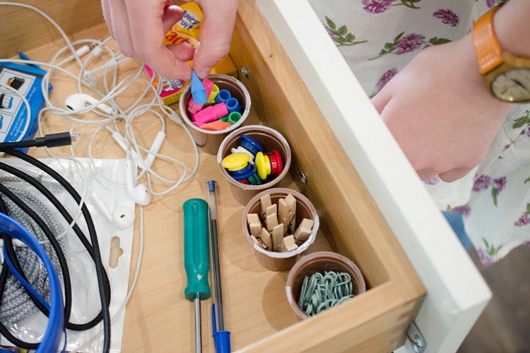A person putting pencil erasers in a K-cup in a drawer.