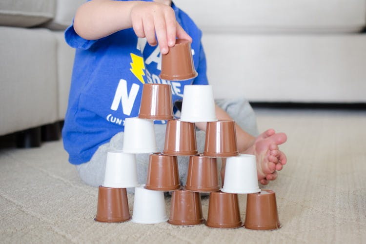 A child building a pyramid with empty K-cups.