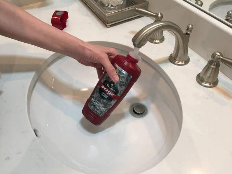 Person adding water to a bottle of old spice body wash.