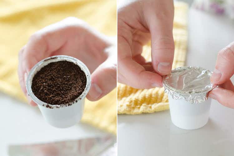 An old K-cup filled with coffee grounds. A person putting aluminum foil over the k-cup.