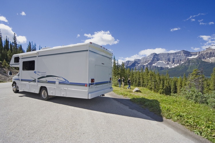An rv parked along side a road in the mountains.