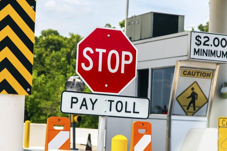 A stop sign with a pay toll sign under it.
