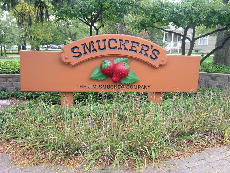 The Smuckers logo on a wooden sign surrounded by grass