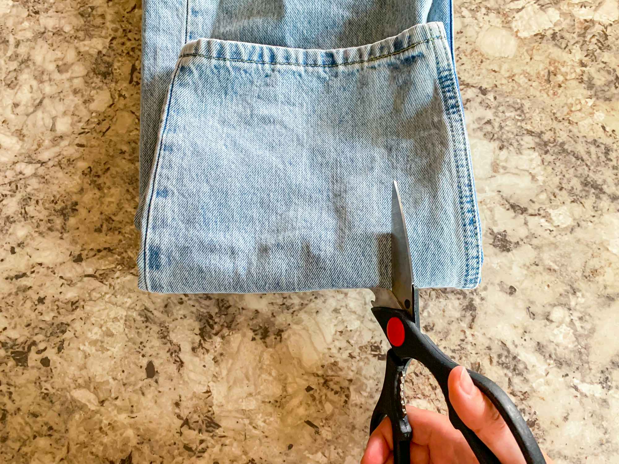 a person cutting strips in jeans with a pair of scissors