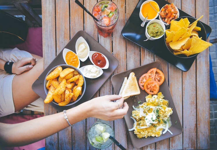 someone holding bread over plates of food