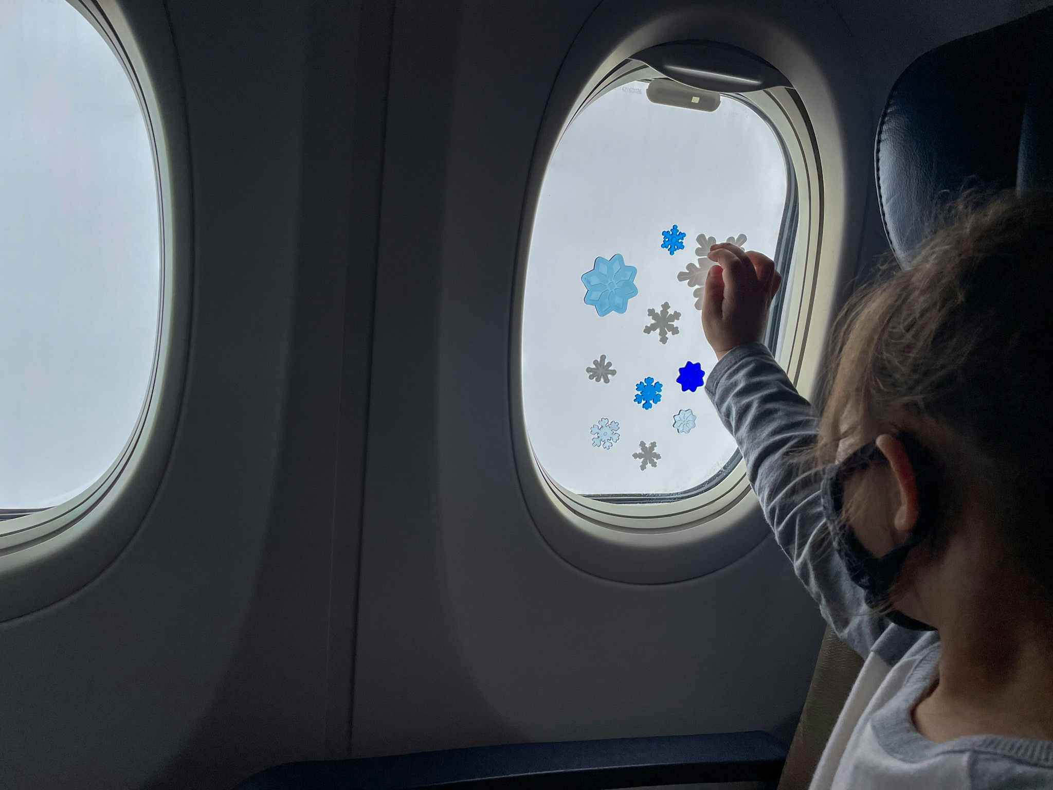 A little girl playing with gel window clings on an airplane