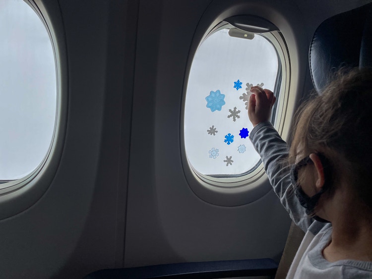 A little girl playing with gel window clings on an airplane