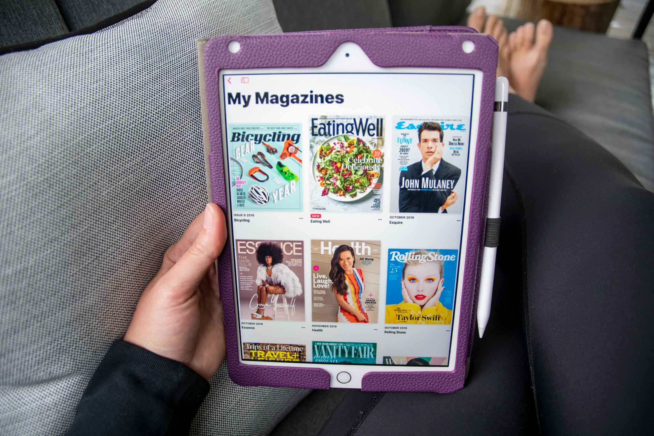 A person sitting with an ipad on their lap displaying digital magazines.