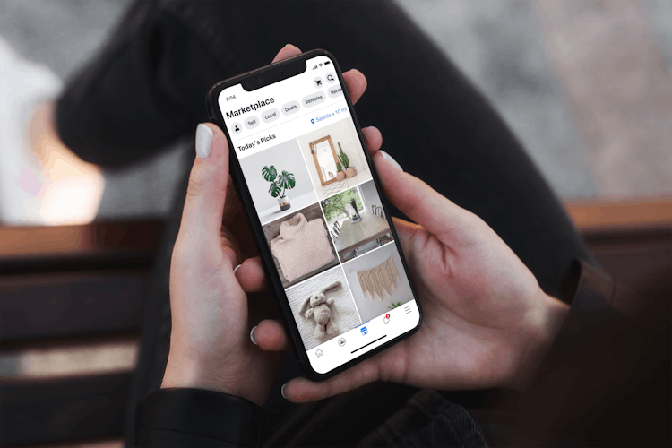 A woman holding a phone displaying facebook market place.