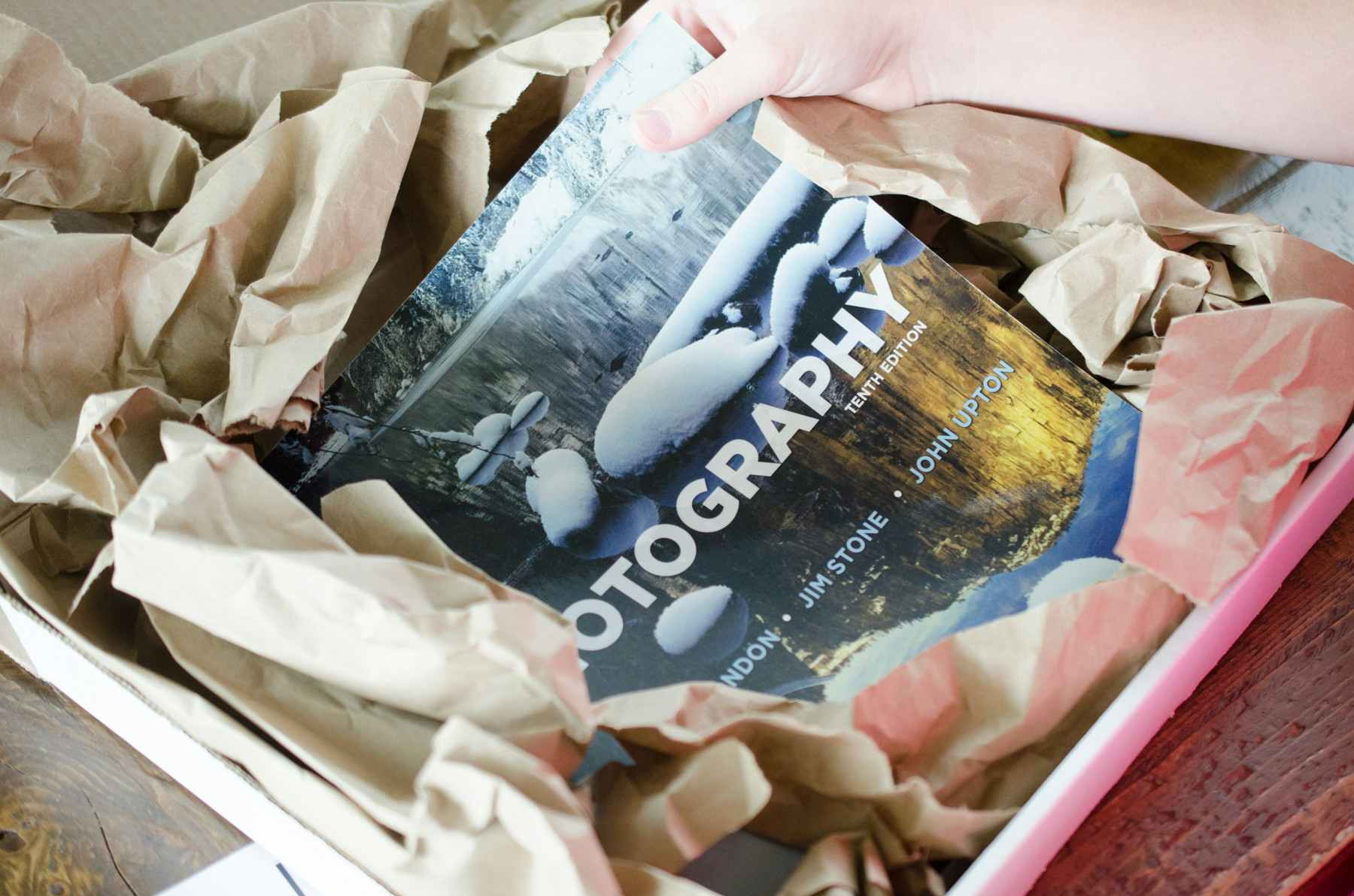 A person packing a photography book into a box