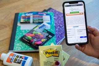 person holding a phone with freecycle on it in front of school supplies