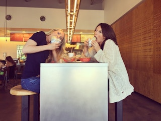 Two women eating burritos at Chipotle