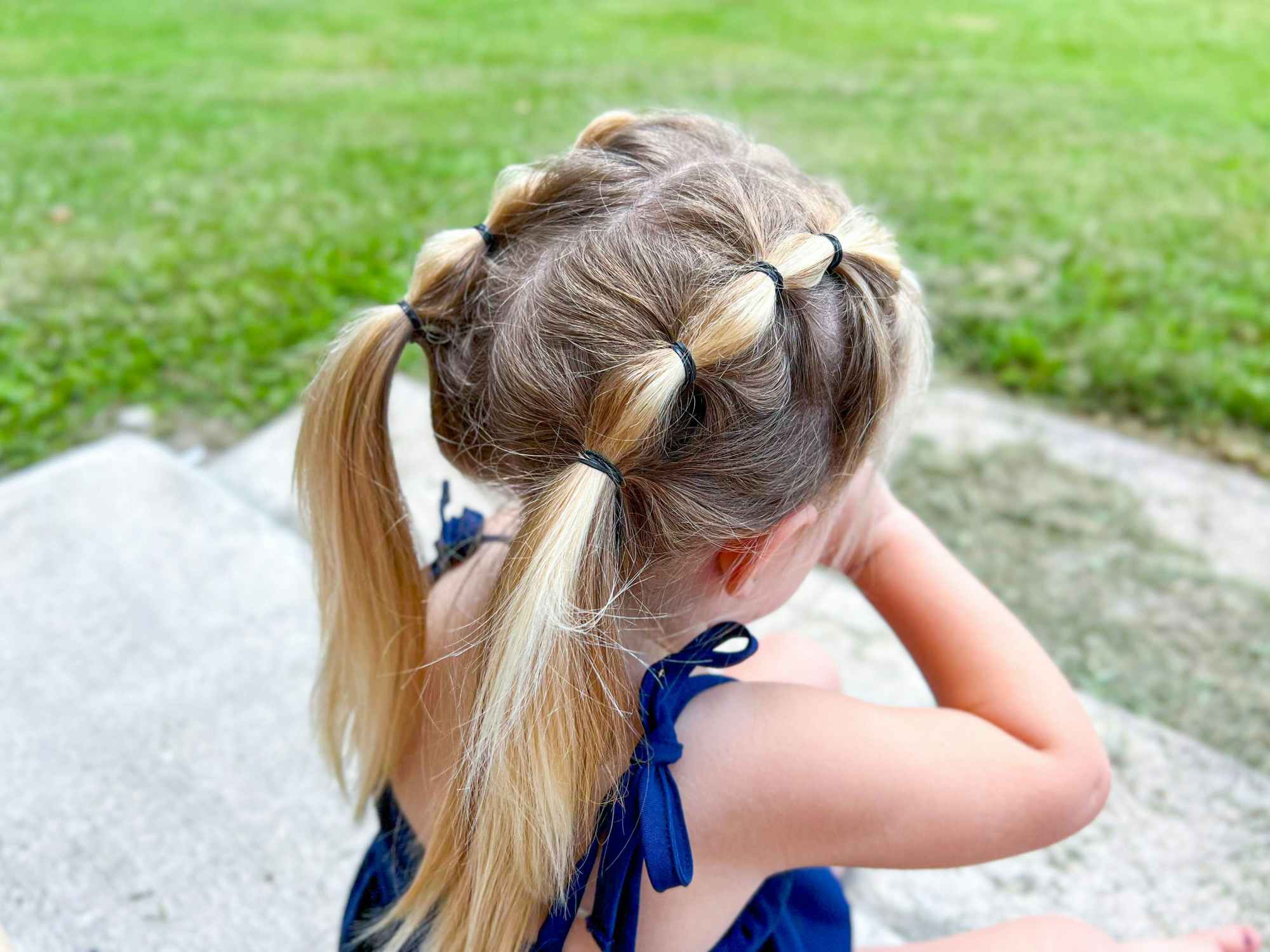 A little girl standing outside, showing off her hairstyle - looped pigtails