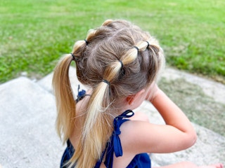A little girl standing outside, showing off her hairstyle - looped pigtails
