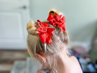 A little girl showing off her hairstyle - two high buns with big red bows
