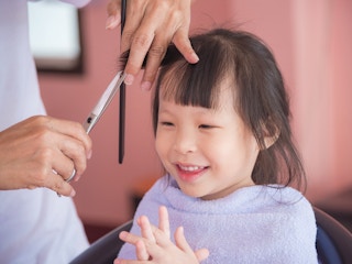 A little girl getting her hair cut at home