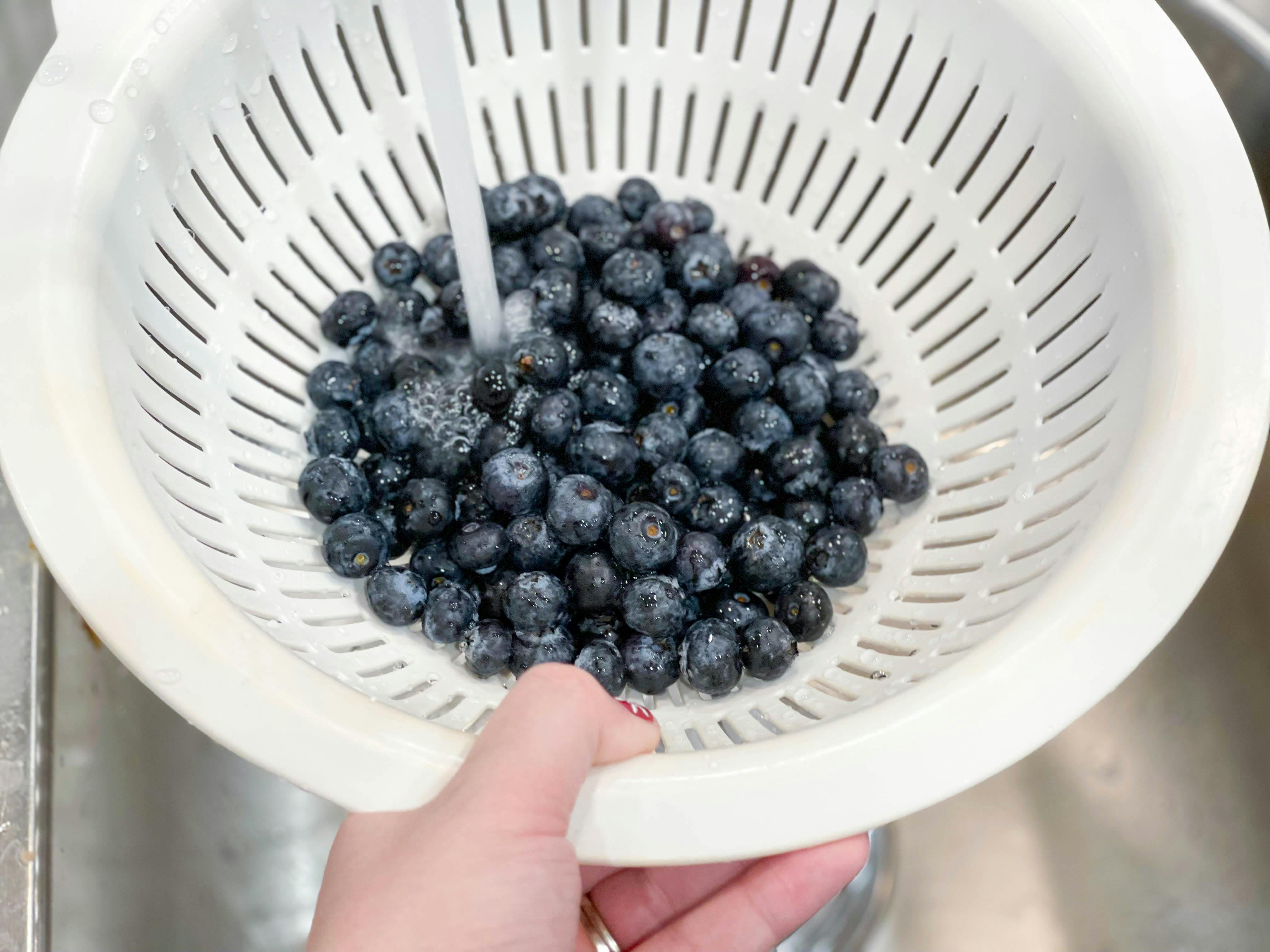blueberries in colander being rinsed