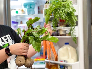 beets and carrots being held in front of fridge