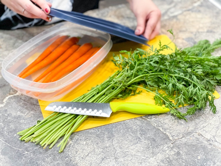 carrots in a tubberware in water with lid being put on