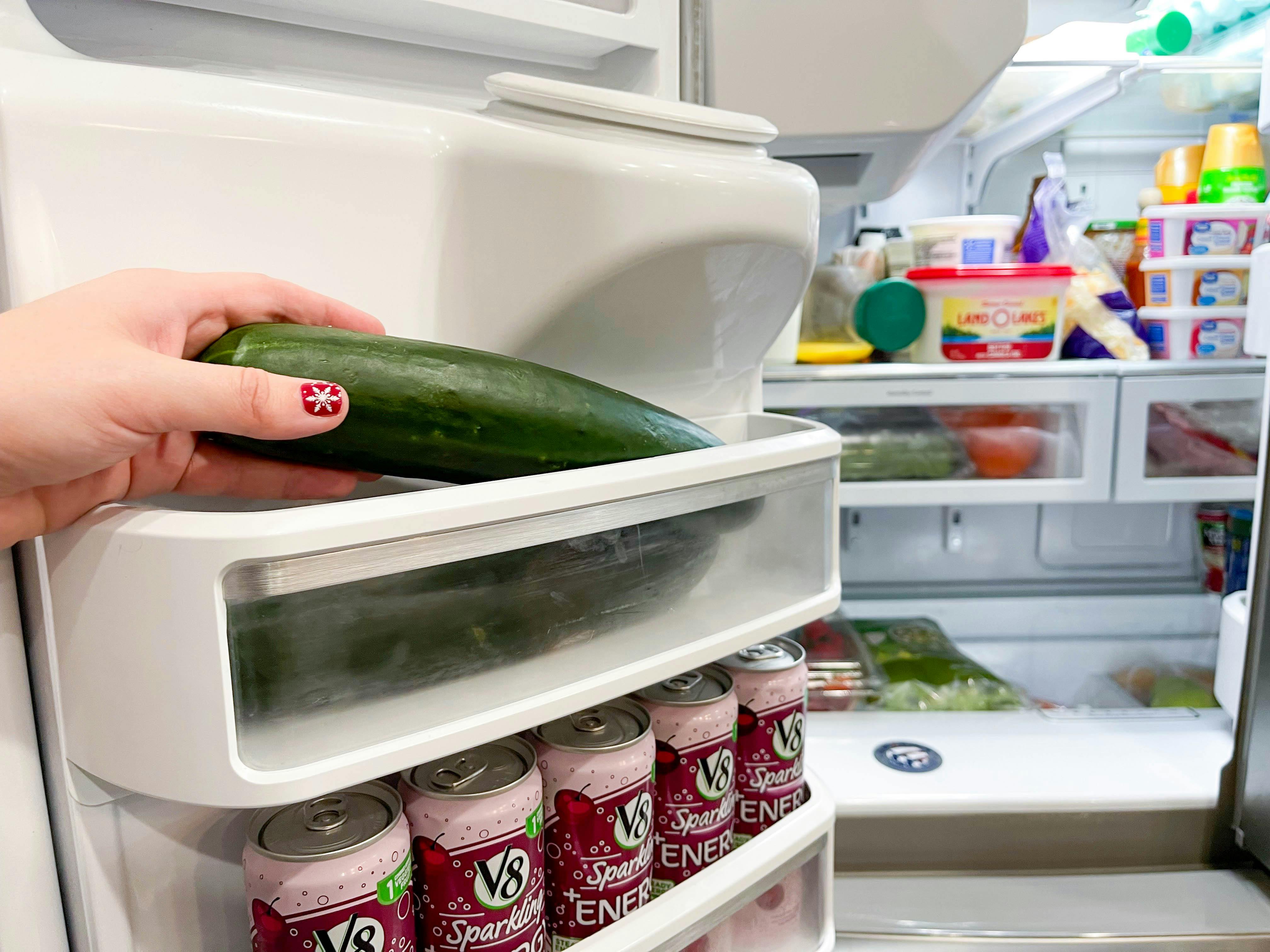 cucumber being placed in fridge door