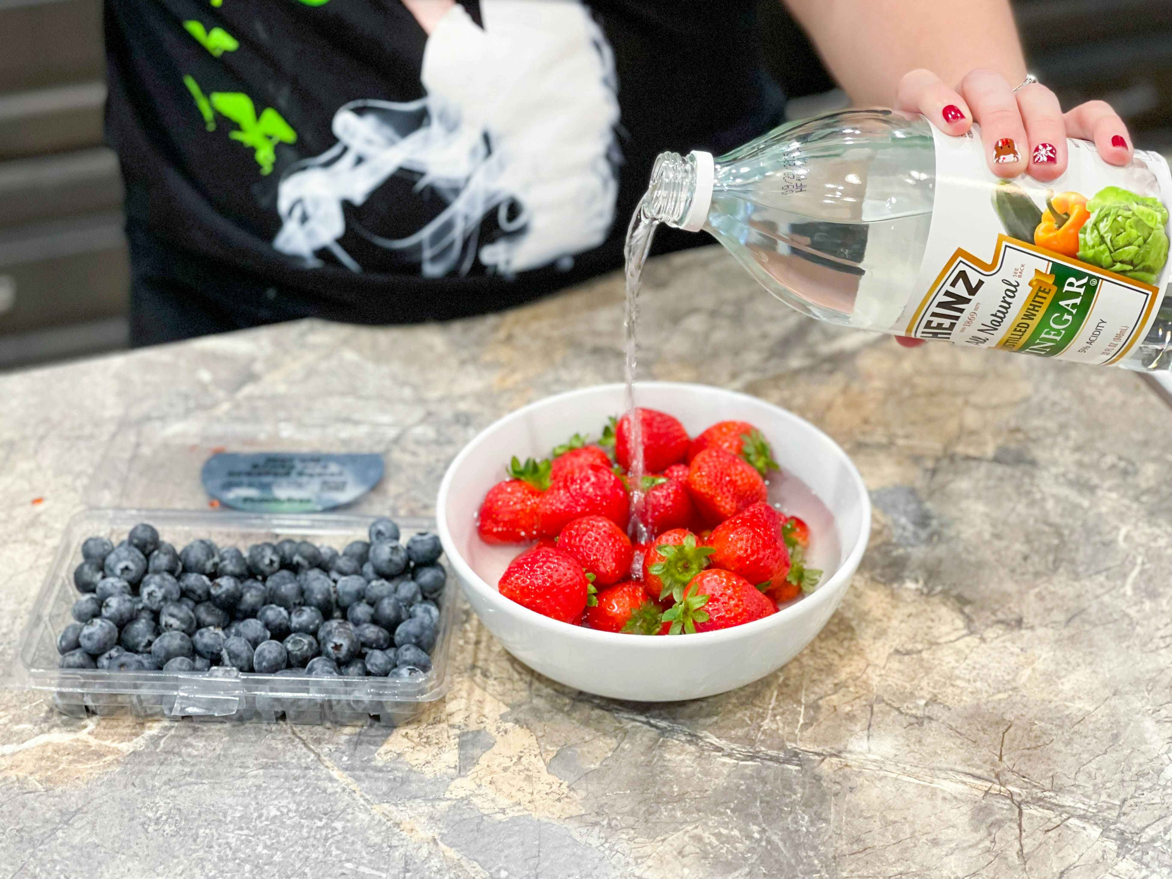strawberries and blueberries with vinegar being poured on