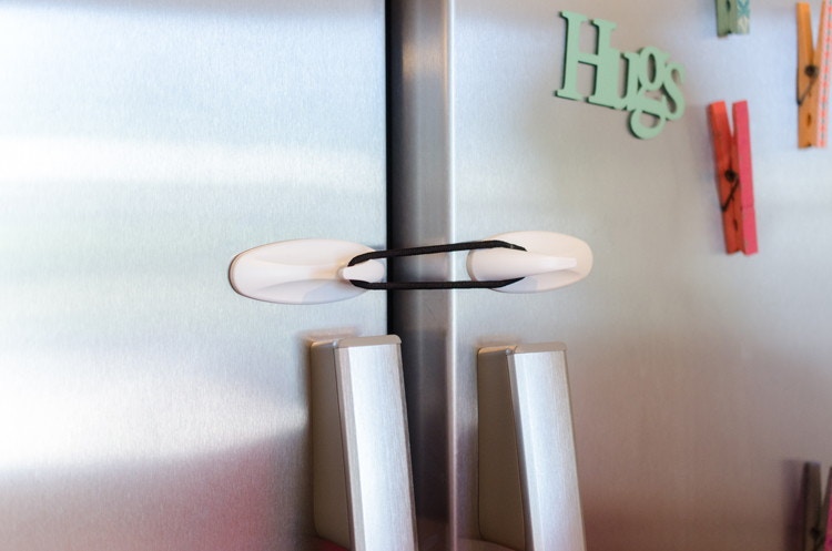 Use Command hooks and a hair tie to childproof your fridge.