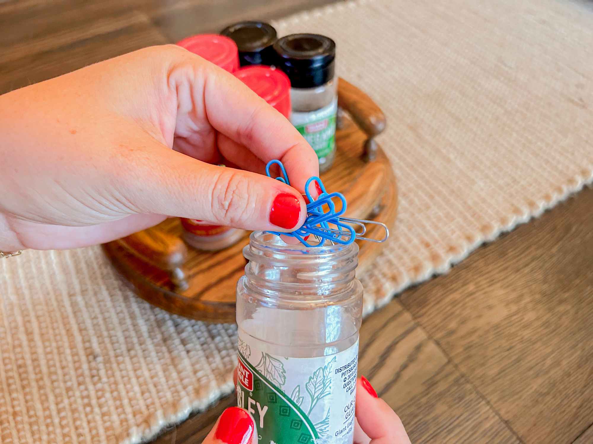 a person putting paper clips into an old spice bottle