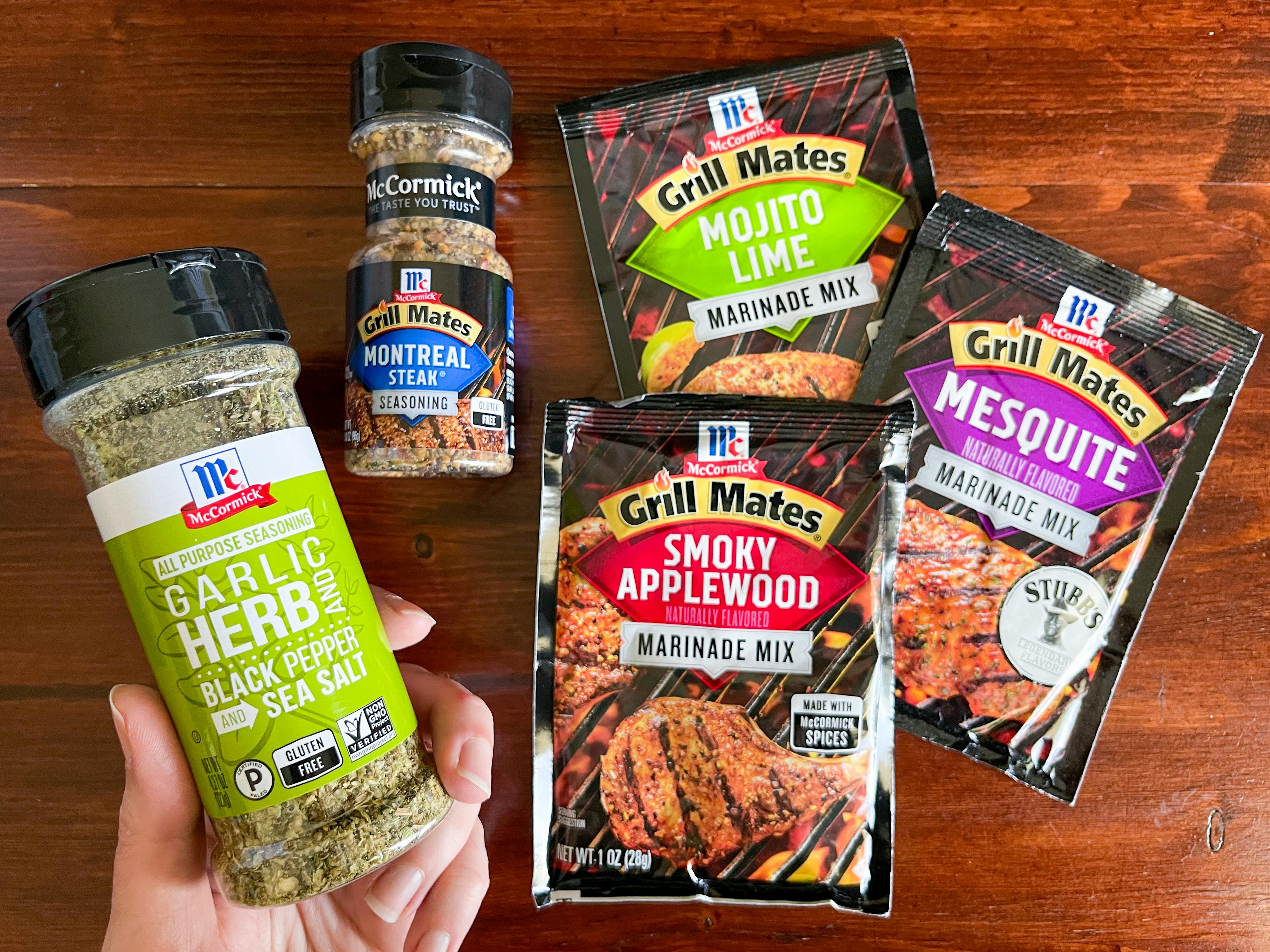 Two bottles and three packets of McCormick seasoning on a wood table top.