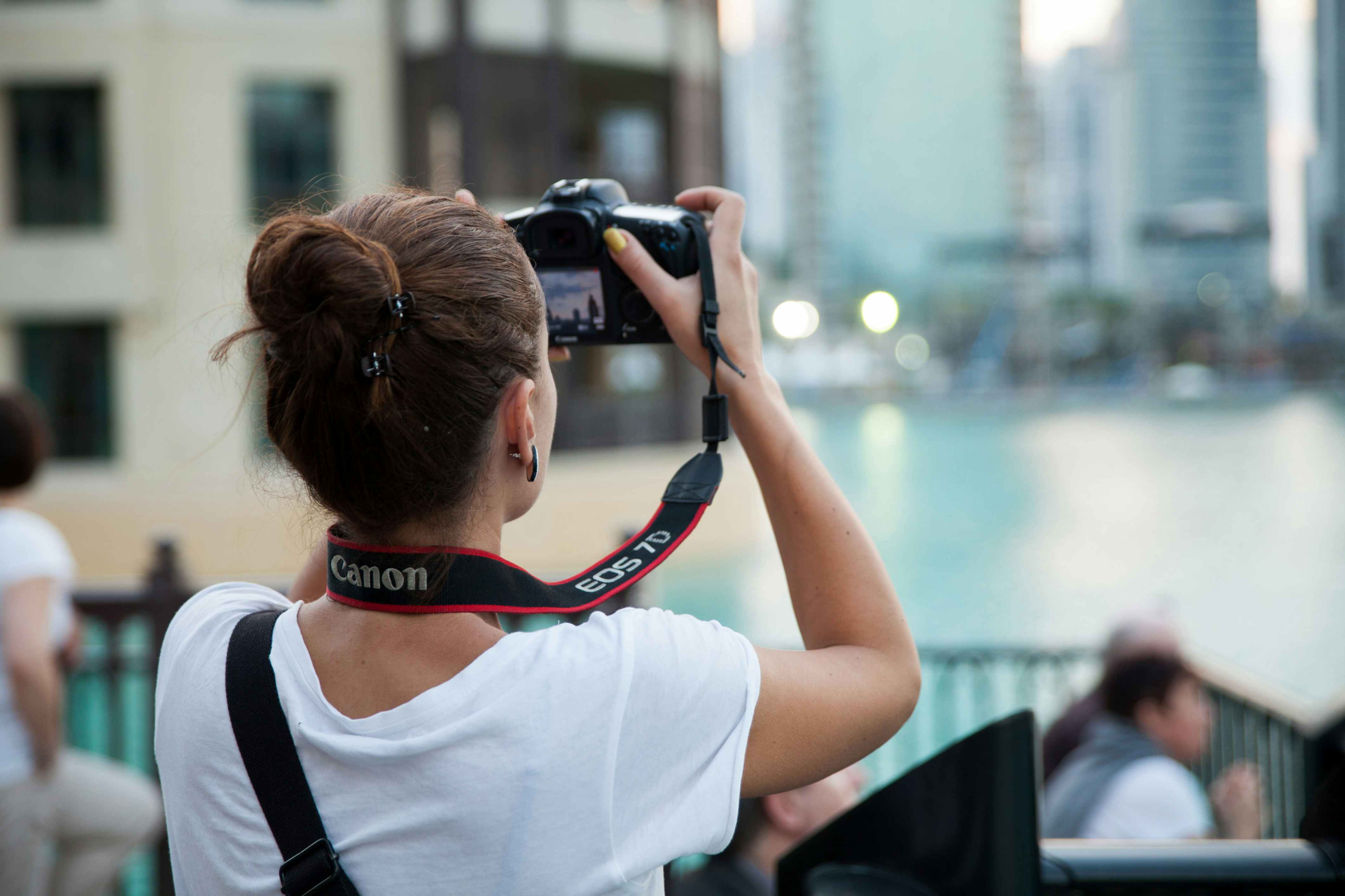 A person with a DSLR camera taking a photo in a city.