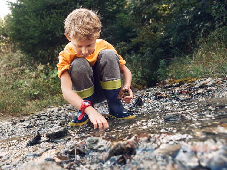 A boy picking up rocks from the ground.