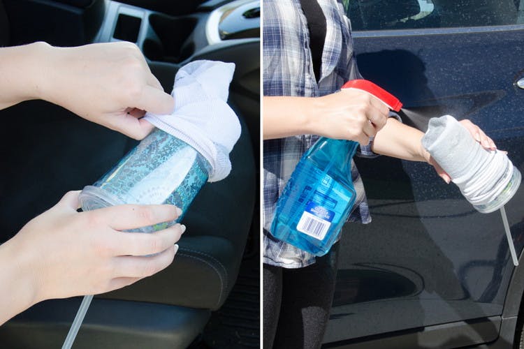 someone using an old sock, Windex, and a travel cup to clean cup holders in their car.